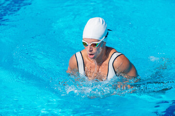 Female swimmer demonstrating breaststroke in outdoor pool. Swimming technique, active woman, water...