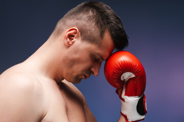 Exhausted boxer leaning head against boxing glove