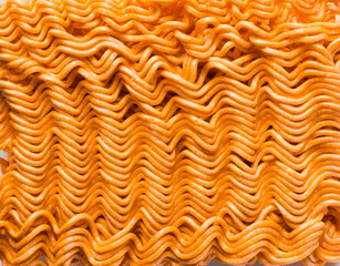 Overhead view of spicy ramen noodles, top view of orange spicy noodles on countertop