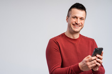 Portrait of smiling middle aged man standing isolated over gray background, using mobile phone