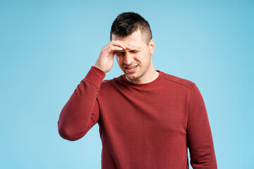Middle aged man touching his forehead from pain having headache standing isolated on blue background