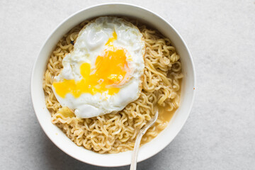 overhead view of a bowl of ramen with a fried egg, top view of a runny egg with noodles