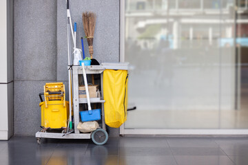 A yellow cleaning cart with a yellow trash bag and a yellow bucket