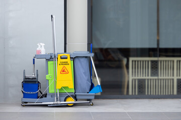 A cleaning cart with a yellow sign on it
