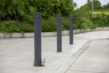 Three black poles are standing in a parking lot