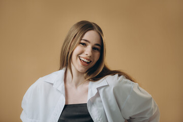 A modern young woman in a fashionable outfit is posing on a beige background.