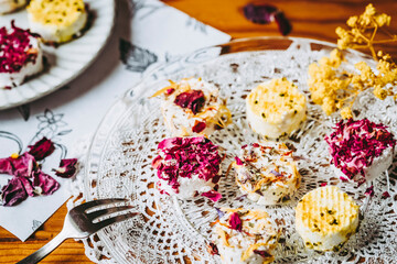 Petits fromages de chèvre frais avec des graines et pétales fait-maison posés dans une assiette