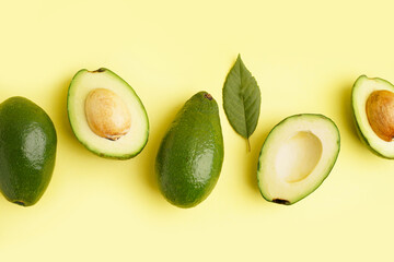 Fresh ripe avocados and leaf on yellow background