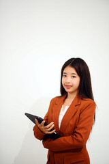 Fototapeta premium Young beautiful Asian woman in business office standing use tablet in hand, Thai girl enjoy browsing for online shopping store with copy space for advertisement, on isolated white background