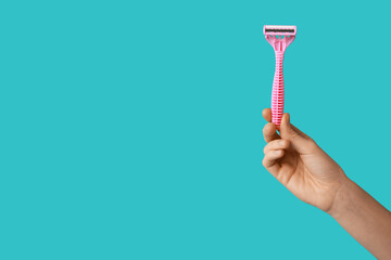 Female hand with razor on turquoise background