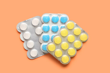 Pills for sore throat on orange background