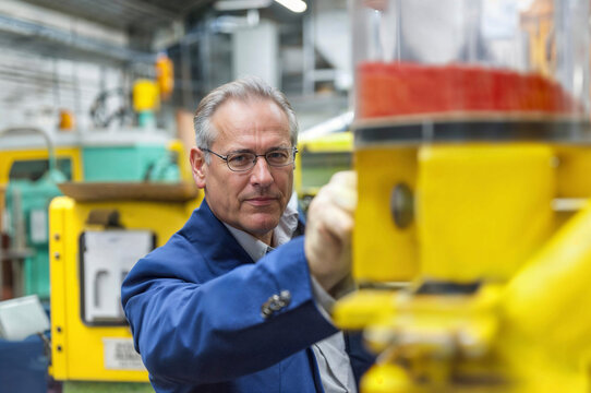 Man with eyeglasses examining machine at warehouse