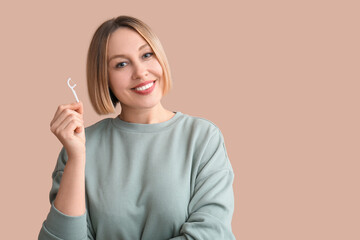 Woman with dental floss pick on beige background