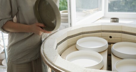 Female Clay Craftsman Placing Bowls in Kiln for Firing