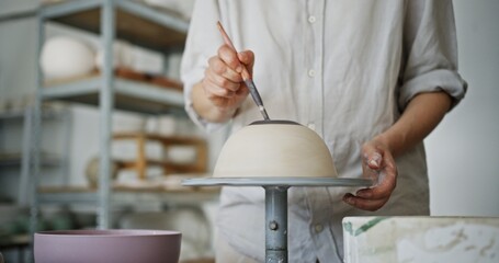 Female Potter Painting a White Clay Bowl in Pottery Studio