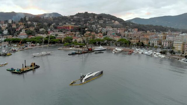 Aerial view of Carlo Riva Marina destroyed by powerful storm. Extreme disaster aftermath, sunken yachts and boats, piles of debris, catastrophic weather events damage. Rapallo, Italy.