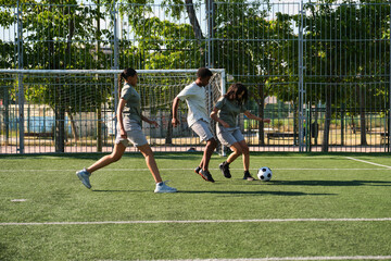 Three young soccer players are running on artificial turf during training session
