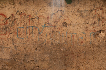 A weathered wall with faded writing in red and blue