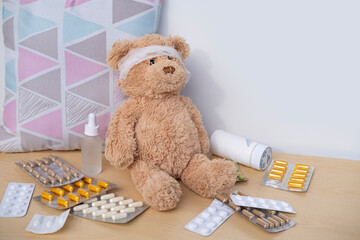 teddy bear with bandaged head, surrounded by scattered medicines and pills, health, care and...