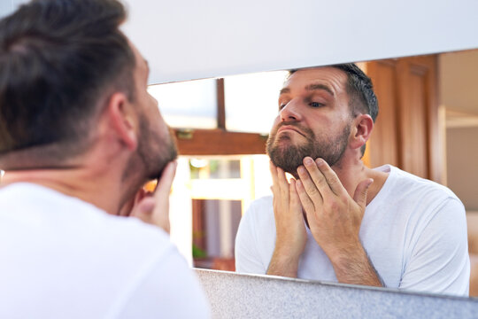 Man, beard and mirror with morning routine in home for grooming, care and hygiene for wellness. Male person, reflection and facial hair for skincare, health and mustache growth in bathroom with pride