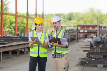 Engineer and foreman worker team with blueprints checking project at the precast concrete factory...