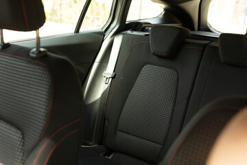 A backseat with black leather seats and red stitching