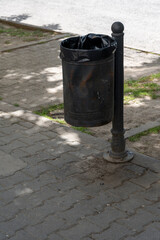 Public rubbish bin in a park - Serbia. Empty trash can in the park. Black bin in park. Black metal...