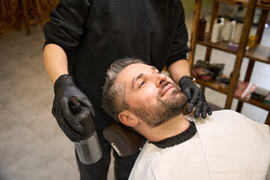 Barber holding bottle with special oil he use to hydrate beard