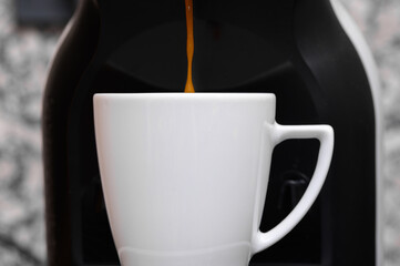 Strumień czarnej kawy wypływa z ekspresu prosto do filiżanki 