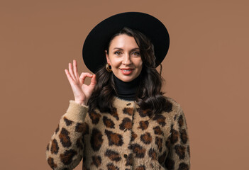 Mature woman with OKAY sign, ok gesture. Happy lady, correct choice on beige