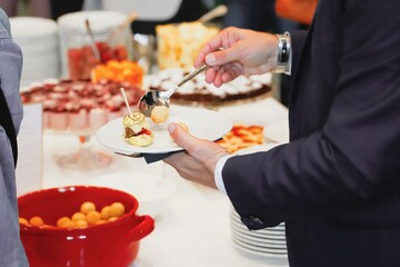 catering buffet food indoor in luxury restaurant with meat and vegetables - Close-up of the hands of a man and a woman holding a plate of food
