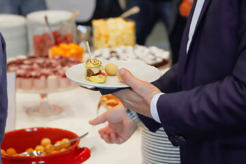 catering buffet food indoor in luxury restaurant with meat and vegetables - Close-up of the hands of a man and a woman holding a plate of food