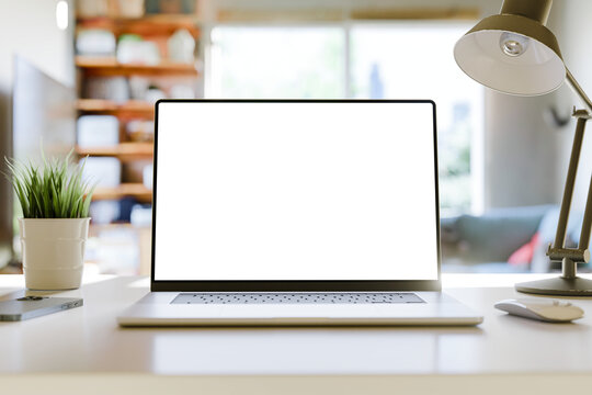 Laptop with a blank screen on a table in a bright home office. Perfect for inserting your own content. 3d render