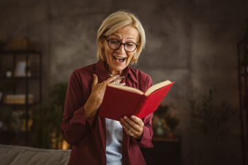 Mature senior relax woman sit in the living room and read a book