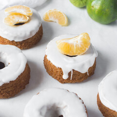 Iced mini bundt cake on a white tray, vanilla bundlette cakes with a clementine lime segment on a white background, small vanilla bundt cakes with an icing glaze