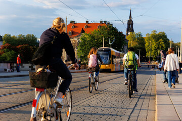 Scenic Dresden cityscape may people riding bikes tram crossing Augustus bridge Elbe river Holy Trinity church Cathedral sunset background. Healthy lifestyle Europe city Germany Saxony capital trip