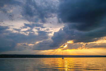 Sonnenuntergang, Sonne strahkt durch düstere Wolken über dem Ammersee, Bayern, Deutschland, Europa