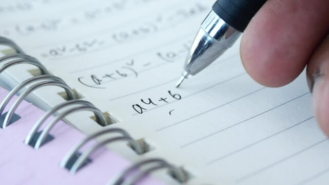 Hand writing algebra equations on a paper 