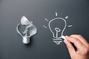 Closeup man draws a new light bulb by chalk instead the real broken one, create a new idea,...