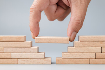 Closeup hand put a wooden piece between the gap of the wall built with wood toy, solution to solve the gap problem