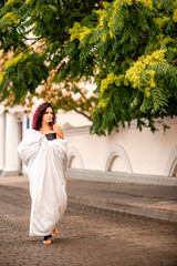 Naklejka premium Woman city blanket. Morning in the big city. A blonde woman in a white blanket is enjoying in the city center. Photographed for social media