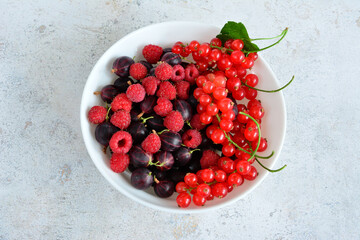 a bowl of raspberries, gooseberries and red currant top view