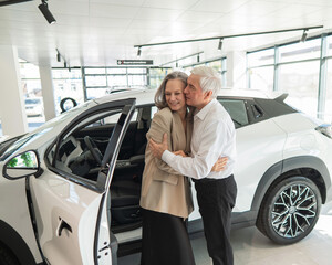 Mature Caucasian couple hugging. Elderly man and woman buying a new car. 