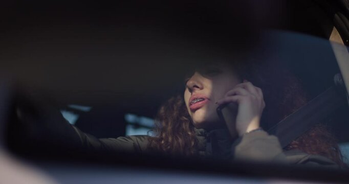 A cheerful young woman with dental braces using her smartphone in the car, exuding happiness and connectivity.
