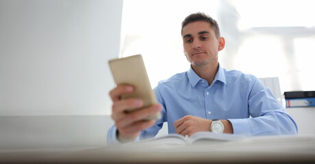 Portrait of concentrated worker using smartphone, chatting or surfing on internet. Kill time at...