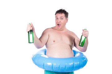 Funny fat man on vacation drinks beer. A guy with an inflatable ring posing on a white background.