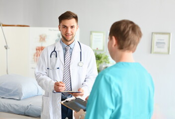 Portrait of head doctor in medical gown hold patient medical history, intern write prescription for...
