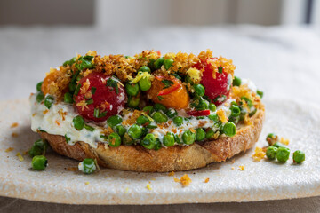 Burrata cheese with grilled green peas, pickled tomatoes and breadcrumbs on toast