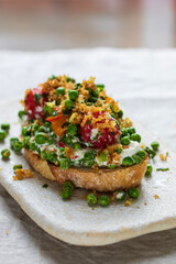Burrata cheese with grilled green peas, pickled tomatoes and breadcrumbs on toast