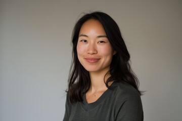 Fototapeta premium Portrait of a smiling asian woman in her 30s sporting a long-sleeved thermal undershirt over minimalist or empty room background
